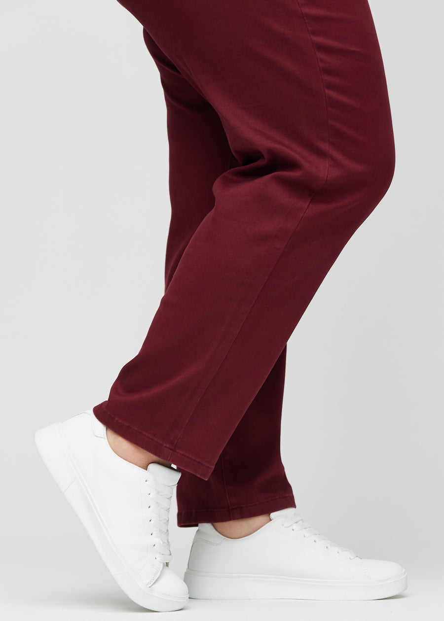 Regular jeans for women in dark red, color Santas. Close-up at the ankles on a plus-size model, showing the straight leg openings.