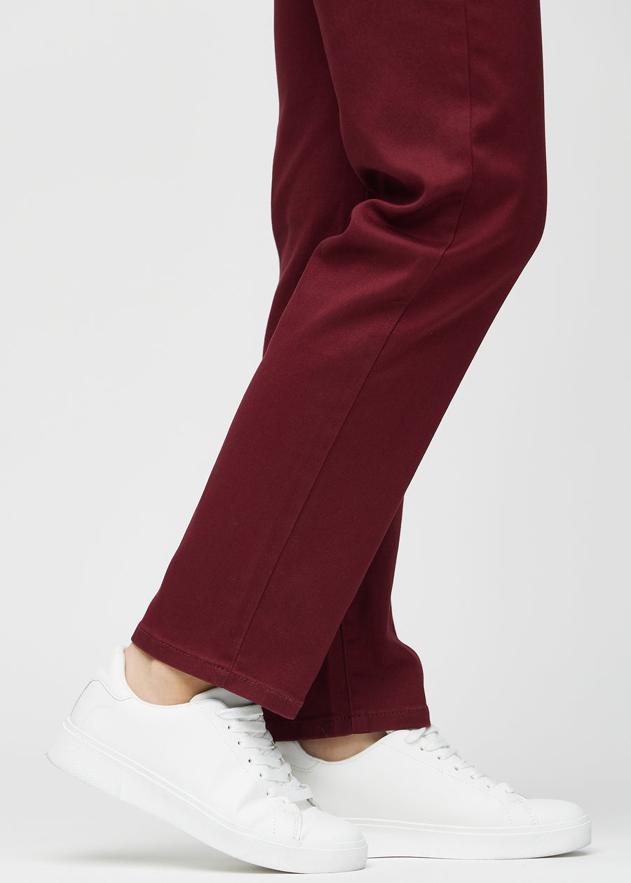 Regular jeans for women in dark red, color Santas. Close-up at the ankles on a model, showing the straight leg openings.