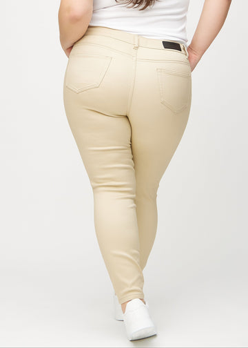 Beige skinny jeans seen from the back on a plus-size model, so the full product can be seen.