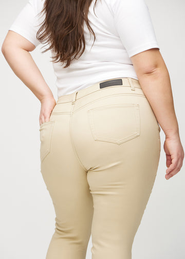 Beige skinny jeans seen from the back close up on a plus-size model to show details.