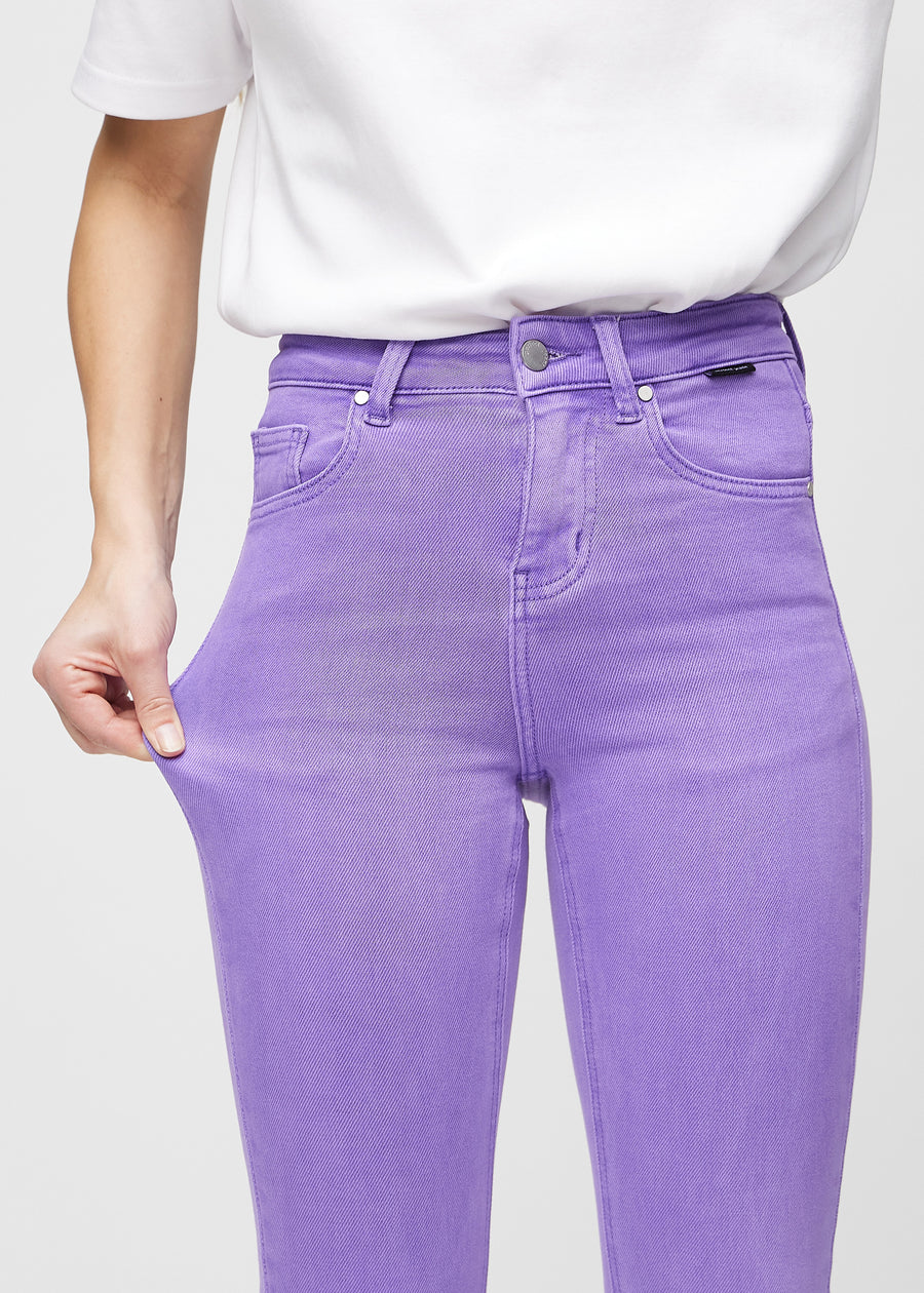 Skinny jeans for women in purple, color Lavenders. A model stretches the jeans at the thigh to show the fabric&