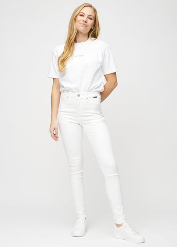 Skinny jeans for women in white, color Marguerites. Full-length view of a model in the jeans.