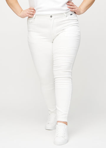 Skinny jeans for women in white, color Marguerites. Front view on a plus-size model, showing the close fit through the legs.