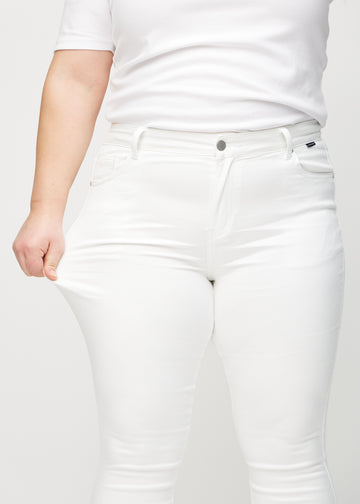 Skinny jeans for women in white, color Marguerites. A plus-size model stretches the jeans at the thigh to show the fabric&