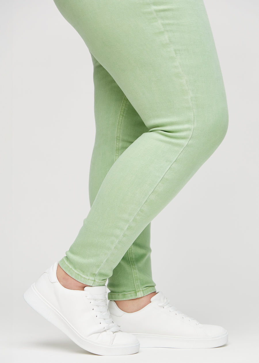 Skinny jeans for women in light green, color Mints. Close-up of the snug-fitting leg openings at the ankles on a plus-size model.