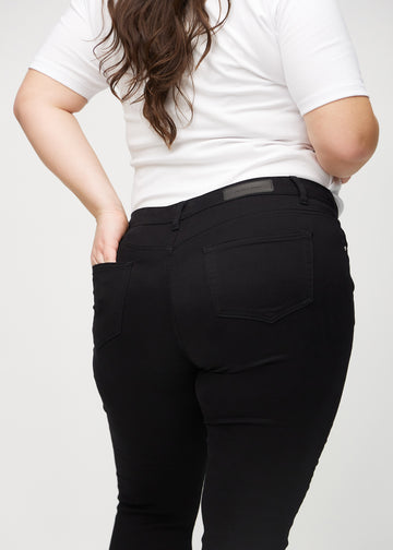 Black skinny jeans seen from the back close up on a plus-size model to show details.