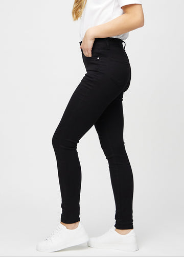 Black skinny jeans seen from the side on a model.