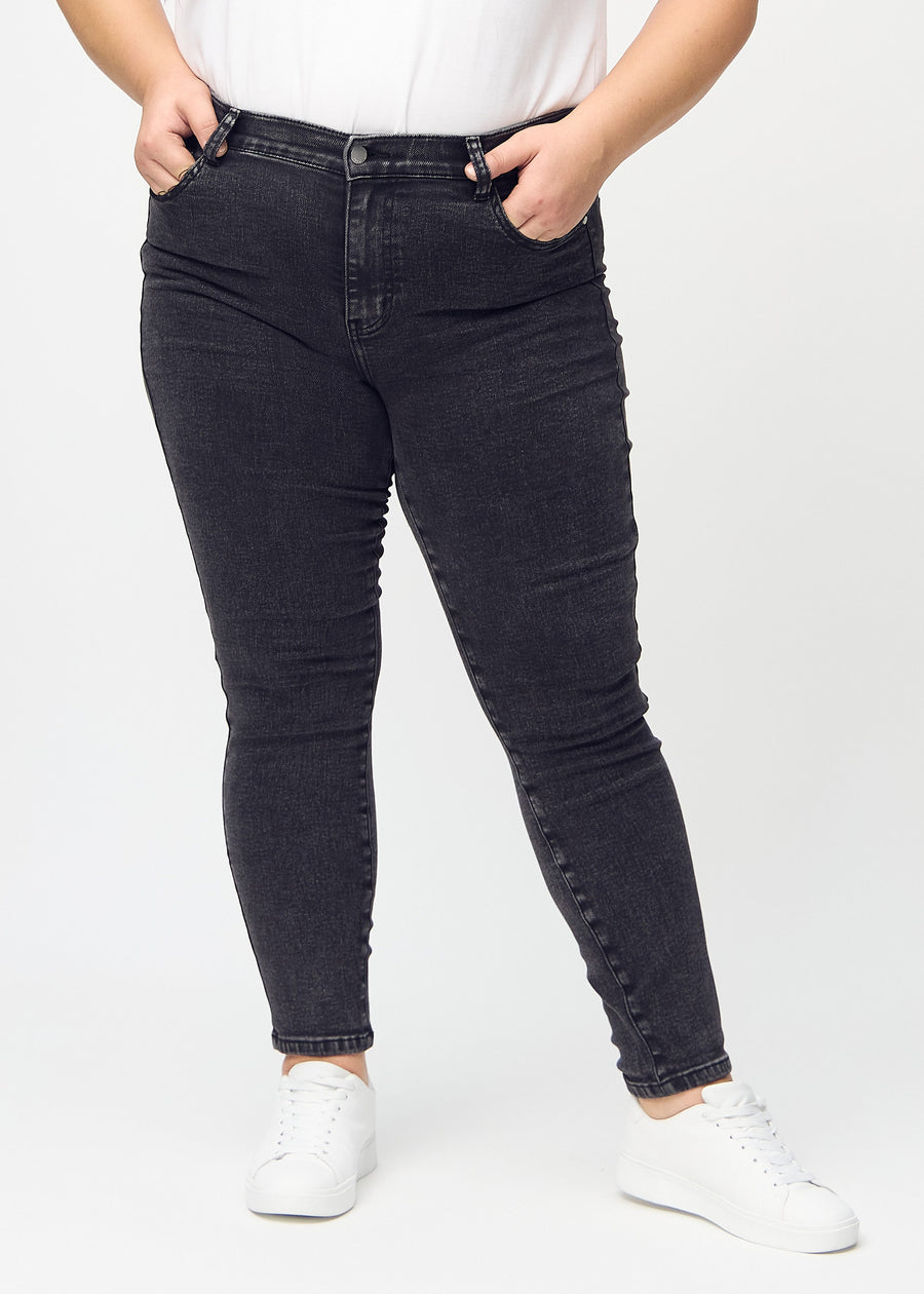 Skinny jeans for women in dark grey, color Shadows. Front view on a plus-size model, showing the close fit through the legs.