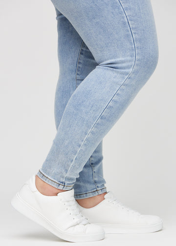 Skinny jeans for women in light blue, color Waves. Close-up of the snug-fitting leg openings at the ankles on a plus-size model.