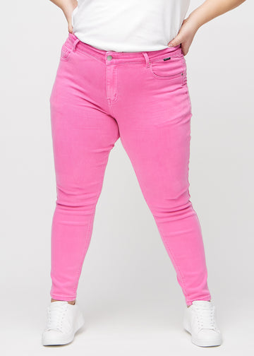 Slim jeans for women in light pink, color Flamingos. Front view on a plus-size model, showing a close fit through the leg with a little more room at the ankle.