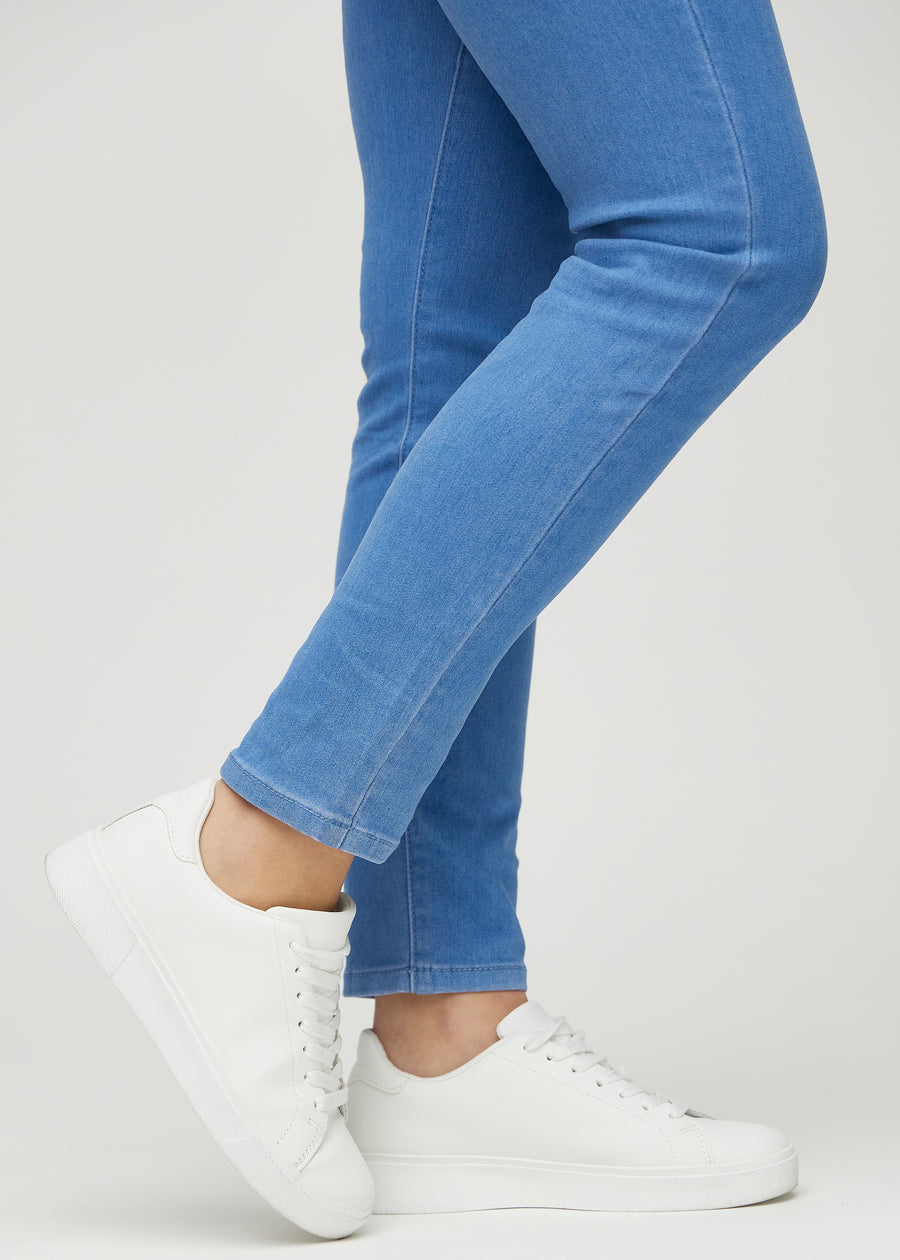 Slim jeans for women in blue, color Geraniums. Close-up at the ankles on a model, showing the fit at the leg openings.