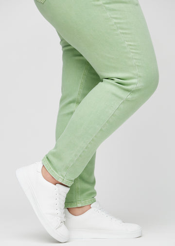 Slim jeans for women in light green, color Mints. Close-up at the ankles on a plus-size model, showing the fit at the leg openings.