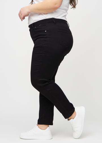 Black slim jeans seen from the side on a plus-size model.