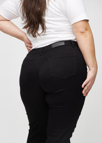 Black slim jeans seen from the back close up on a plus-size model to show details.