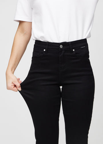 The model stretches the jeans at the thigh to show the stretch.