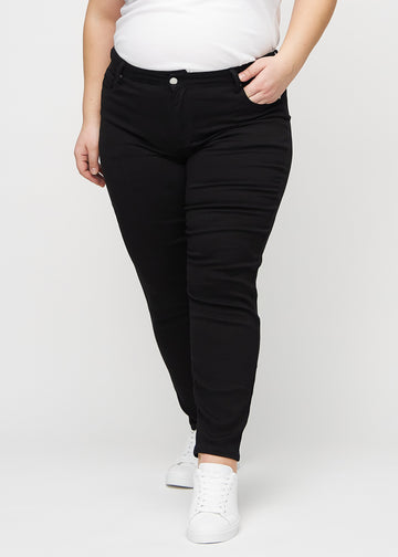 Black slim jeans, model name Ravens, which fit closely to the leg, though slightly looser at the ankle, on a plus-size model, seen from the front.