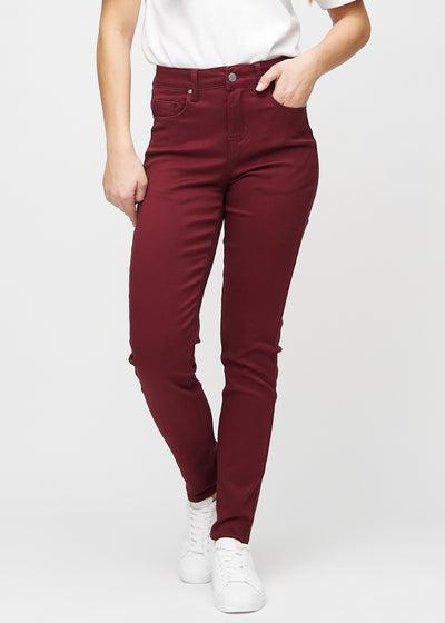 Slim jeans for women in dark red, color Santas. Front view on a model, showing a close fit through the leg with a little more room at the ankle.