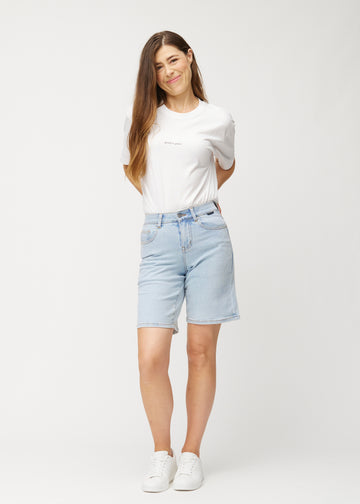 Full-length view of a model wearing light blue Waves denim shorts for women with a mid-rise waist and loose fit.