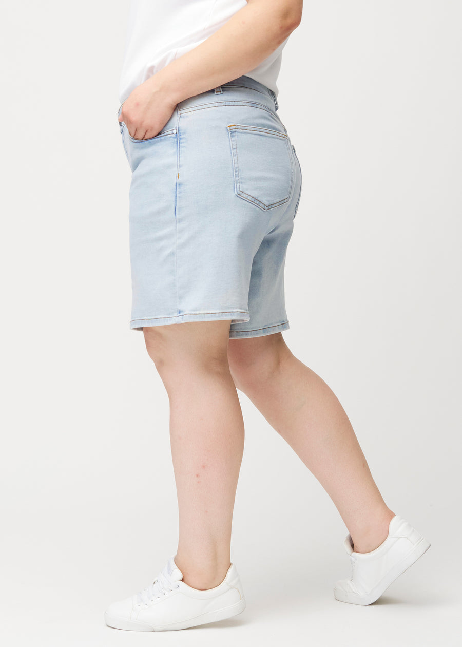 Side view of a female model wearing light blue Waves denim shorts with a mid-rise waist and loose fit.