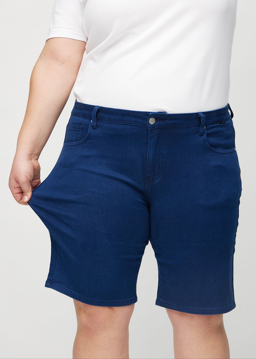 The plus-size model stretches the shorts at the thigh to show the stretch.