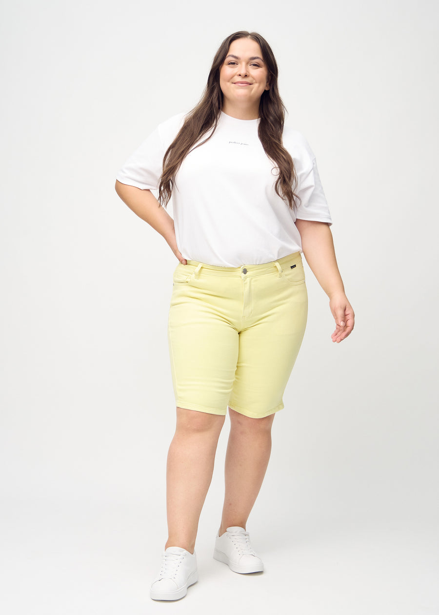 Full image of a plus-size model in light yellow skinny middle shorts.