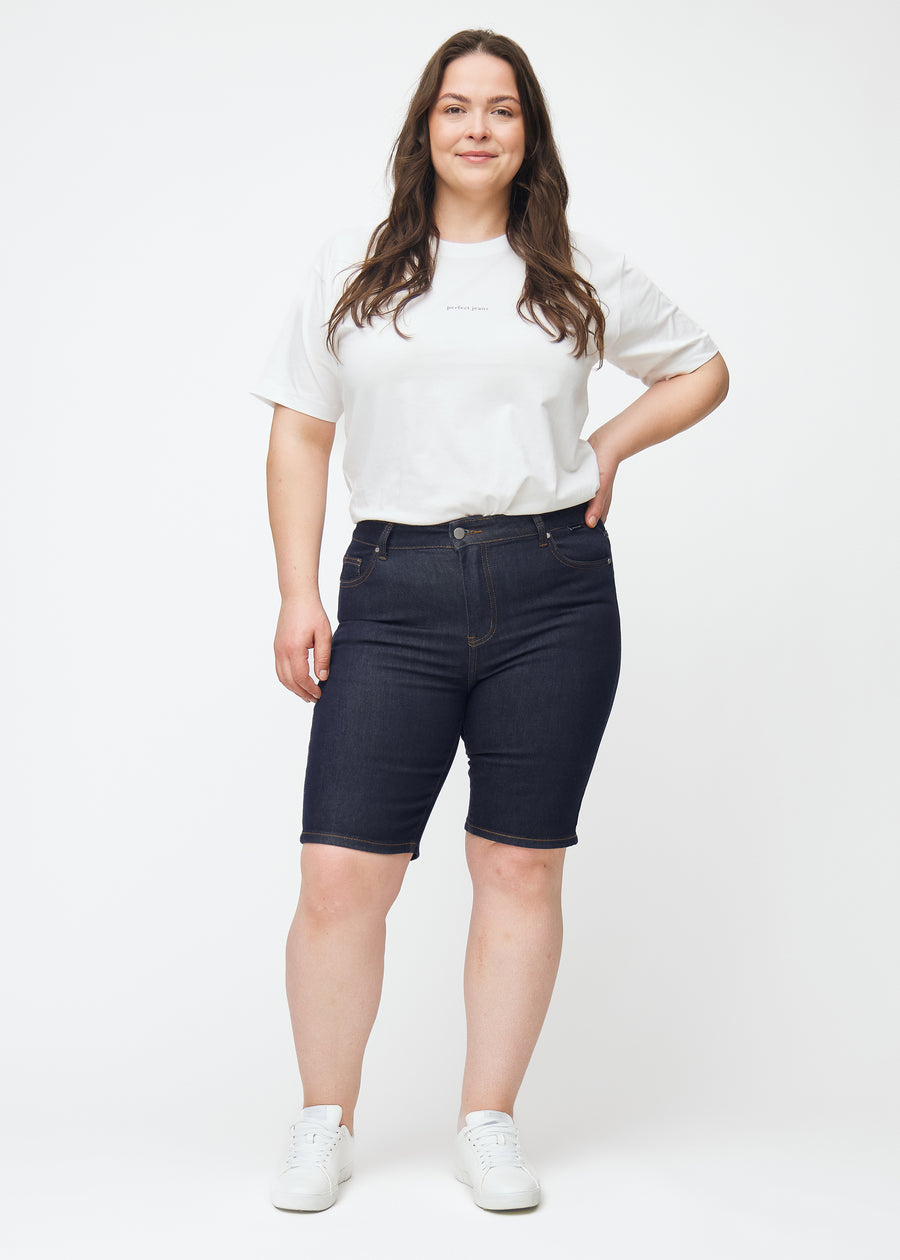 Full image of a plus-size model wearing deep dark blue denim shorts for women in the colour Midnights with a skinny fit.