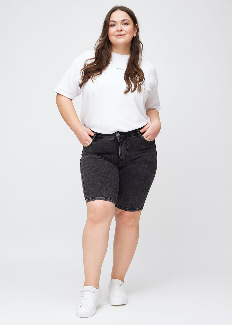 Full image of a plus-size model in dark grey denim skinny middle shorts.