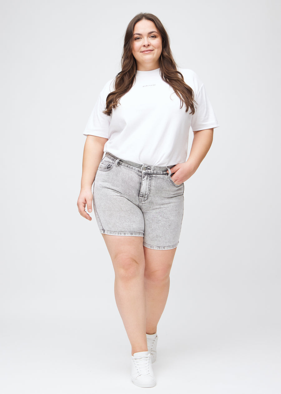 Full image of a plus-size model in light grey denim skinny short shorts.
