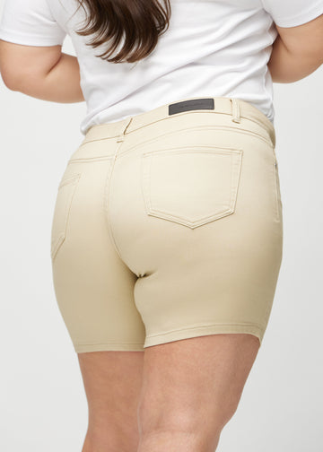 Beige skinny short shorts seen from the back close up on a plus-size model to show details.