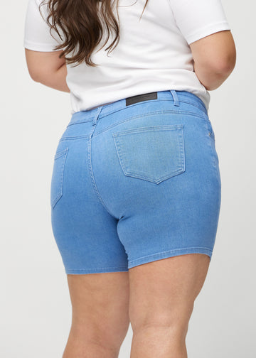 Blue skinny short shorts seen from the back in close-up on a plus-size model to show details.
