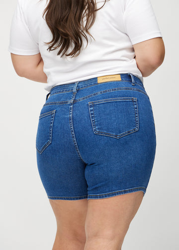 Dark denim skinny short shorts seen from the back close up on a plus-size model to show details.