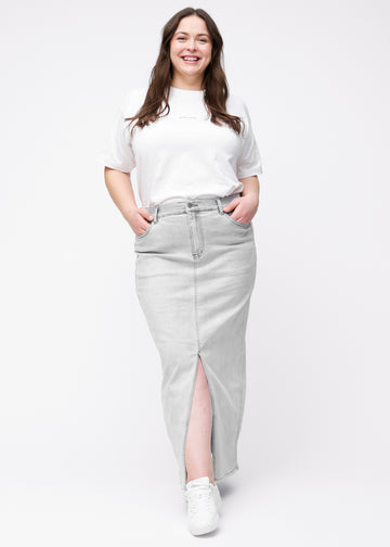 Long light grey denim skirt for women in the color Ashes. Full-length view of a plus-size model wearing the skirt with a front slit.