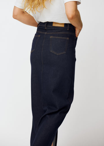 Long deep dark blue denim skirt for women in the colour Midnights seen from the back in close-up to show fit and details.