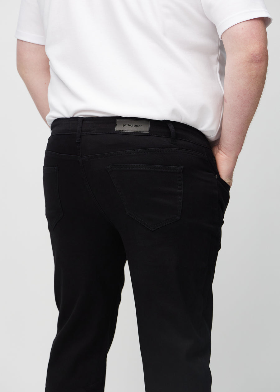 Black regular jeans seen from the back in a close-up on a plus-size model to show details.