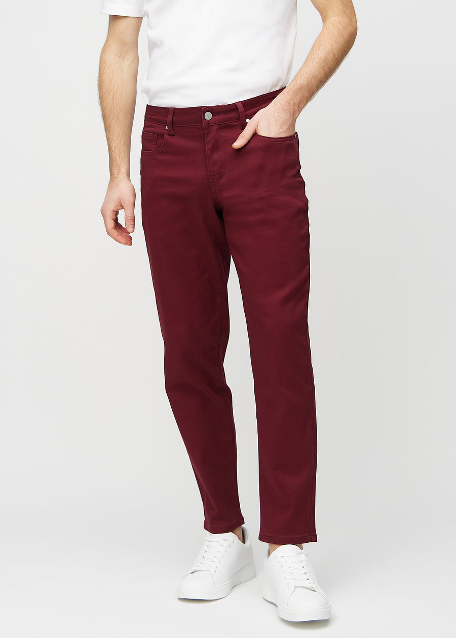 Dark red regular jeans, model name Santas, which goes straight down the leg, seen from the front.