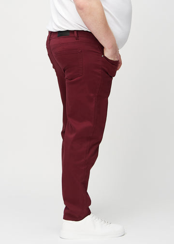 Dark red regular jeans seen from the side on a plus-size model.