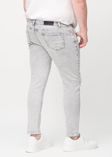 Light grey denim slim jeans viewed from the back on a plus-size model to show the full product.
