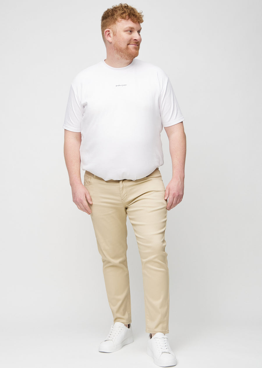 Full-length view of a plus-size model in beige slim jeans.