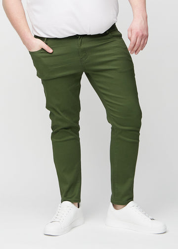 Dark green slim jeans, model name Renewals, fitted closely along the legs on a plus-size model, front view.