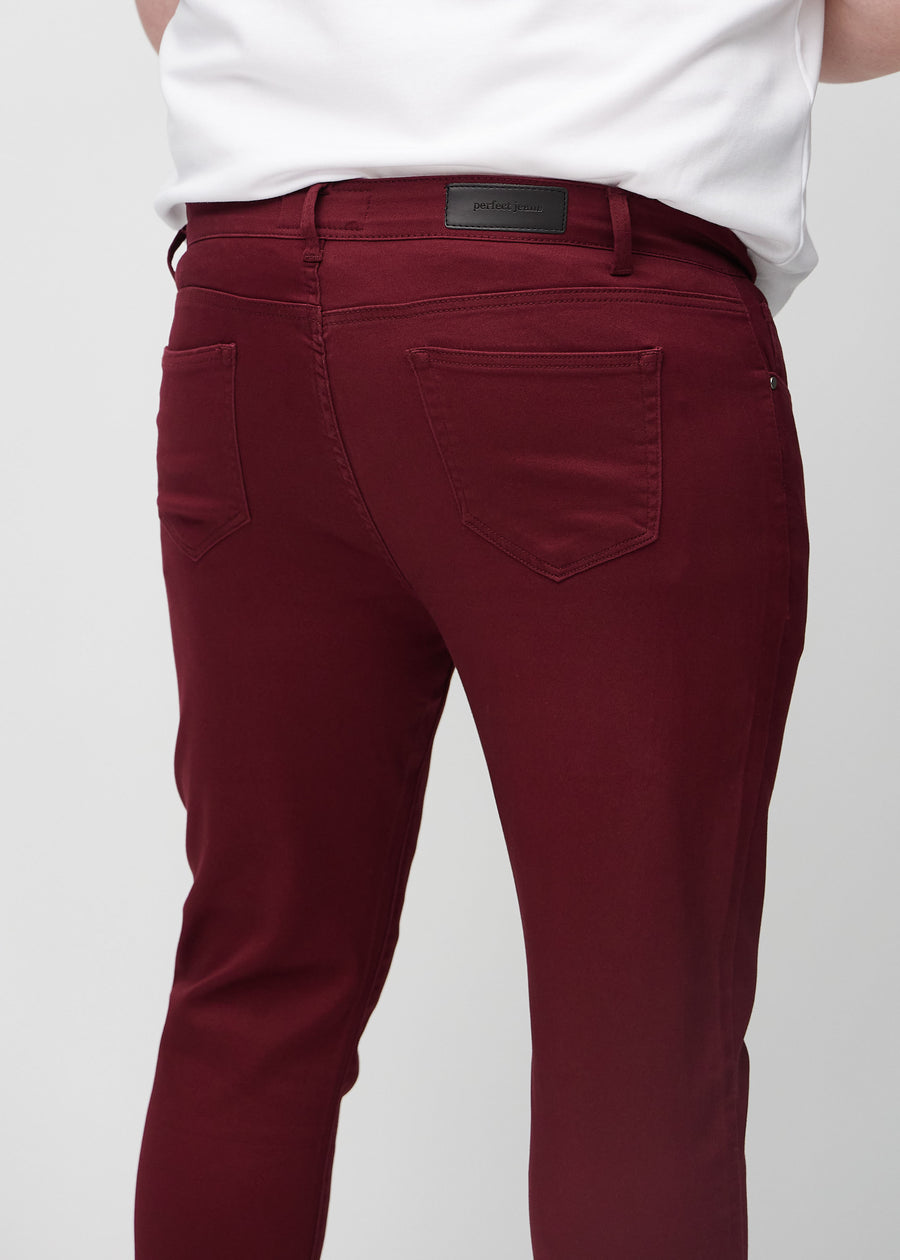 Close-up back view of dark red slim jeans on a plus-size model showing details.