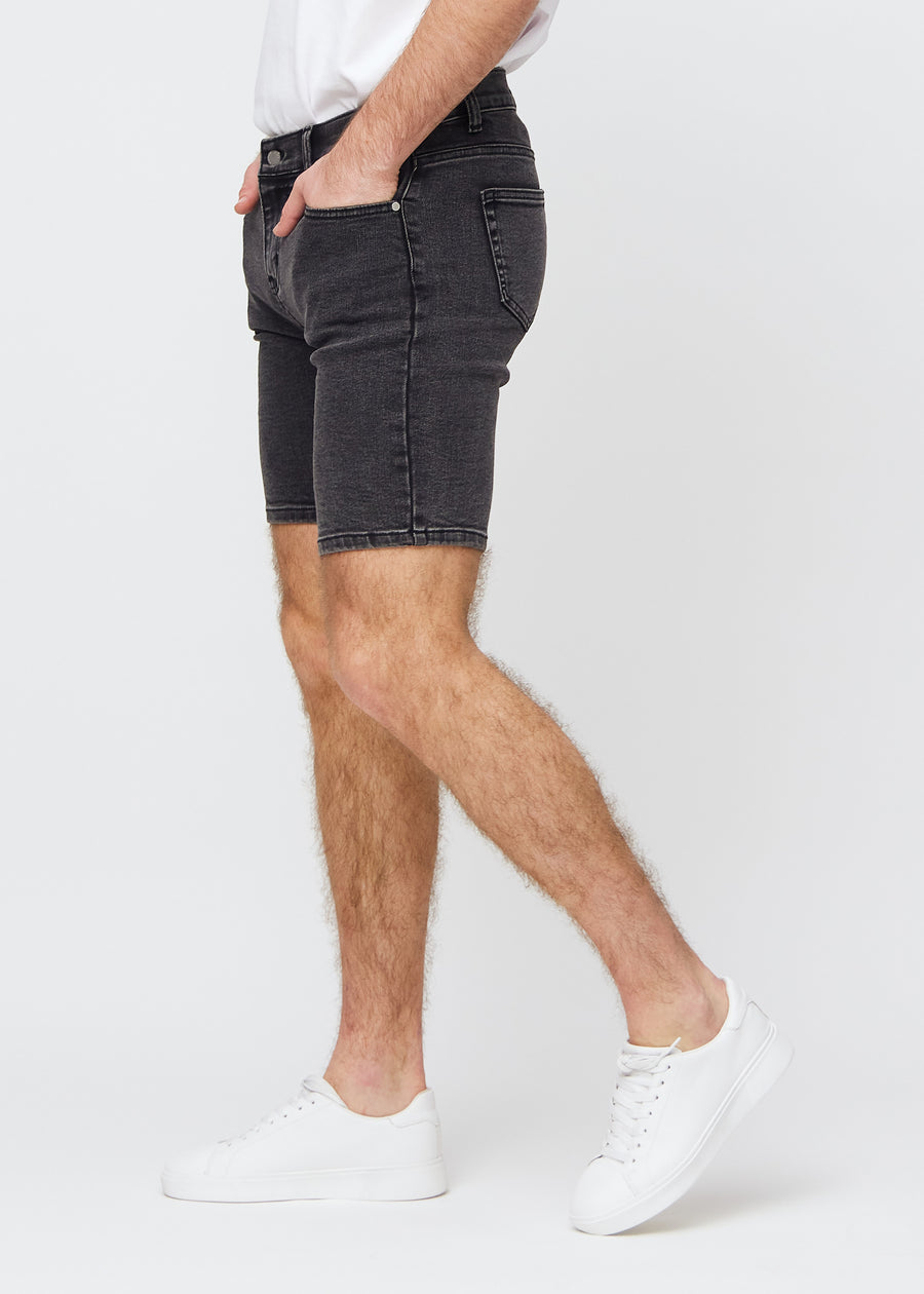 Dark grey denim middle-slim shorts seen from the side on a model.