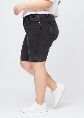 Mørkegrå denim skinny middle shorts set fra siden på en plus-size model.
