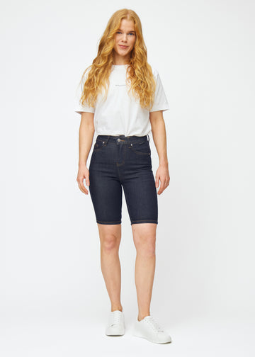 Model viser dyb mørkeblå denim shorts til kvinder i farven Midnights med skinny pasform i bevægelse.