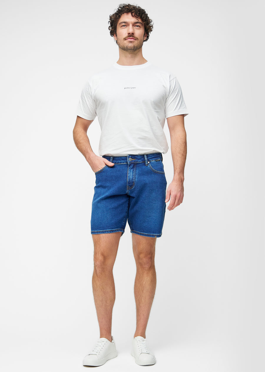Model viser mørkeblå denim shorts til mænd i farven Oceans med regular pasform i bevægelse.